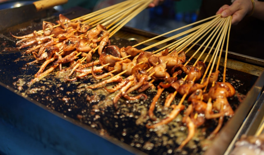 Các que xiên đủ loại khác nhau được nướng trực tiếp trên bếp than hồng rực, tỏa ra mùi thơm lừng khắp cả con phố