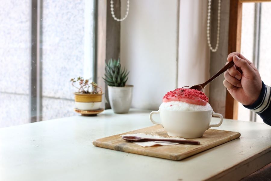 Kem tuyết Bingsu được  điểm xuyến thêm một chút hương vị ngọt ngào và sắc hồng bắt mắt của những cánh hoa anh đào