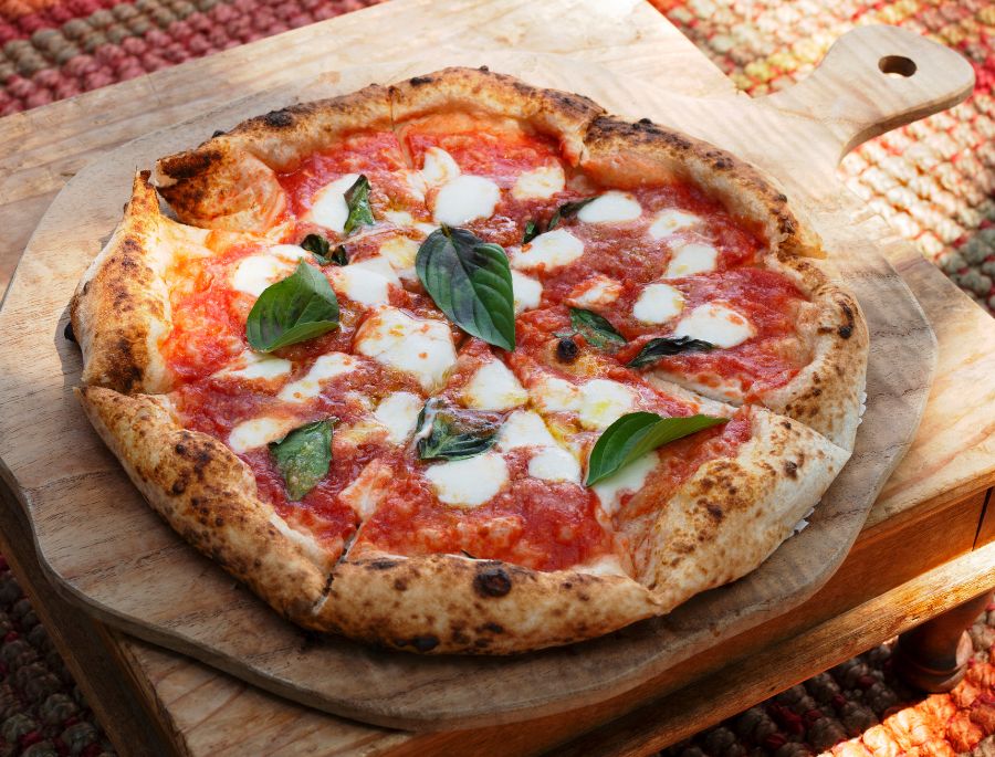 Pizza Margherita, với lớp đế mỏng và topping đơn giản từ cà chua, mozzarella và húng quế,