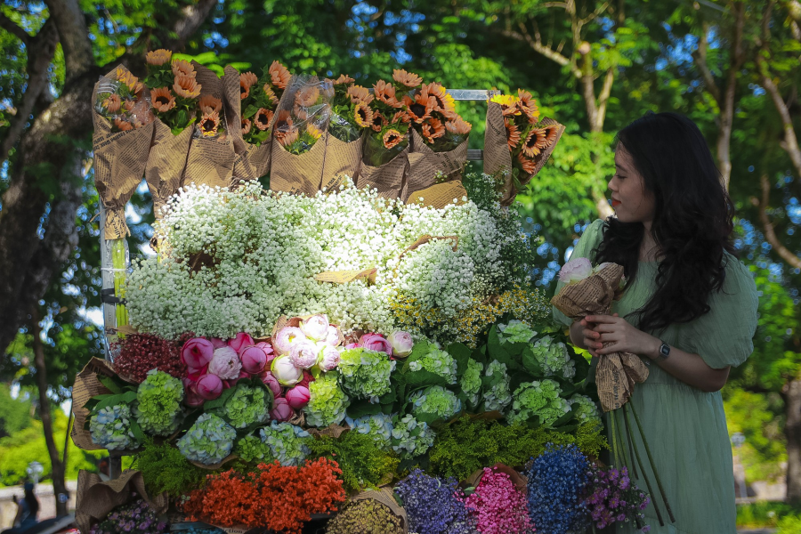 Nếu bạn là một người ngại nhìn vào máy ảnh thì có thể thử chọn cách tạo dáng như giả vờ mua hoa hoặc ngắm hoa