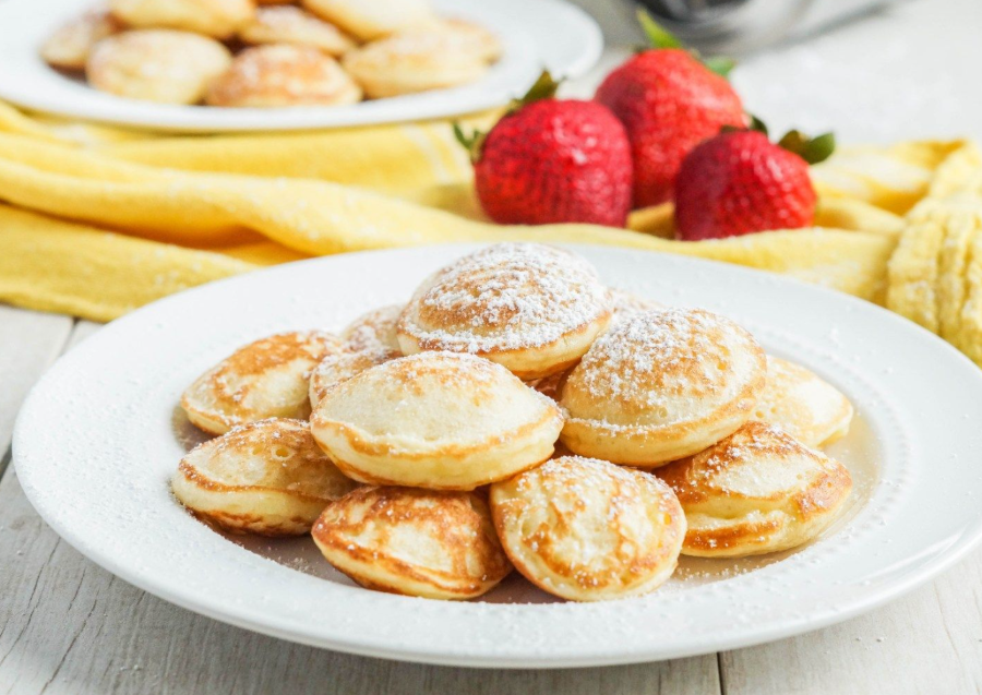 Kích thước của Poffertjes chỉ bé bằng đồng xu, với vẻ ngoài tròn trịa, vàng ươm, toát lên sự ấm áp và hấp dẫn