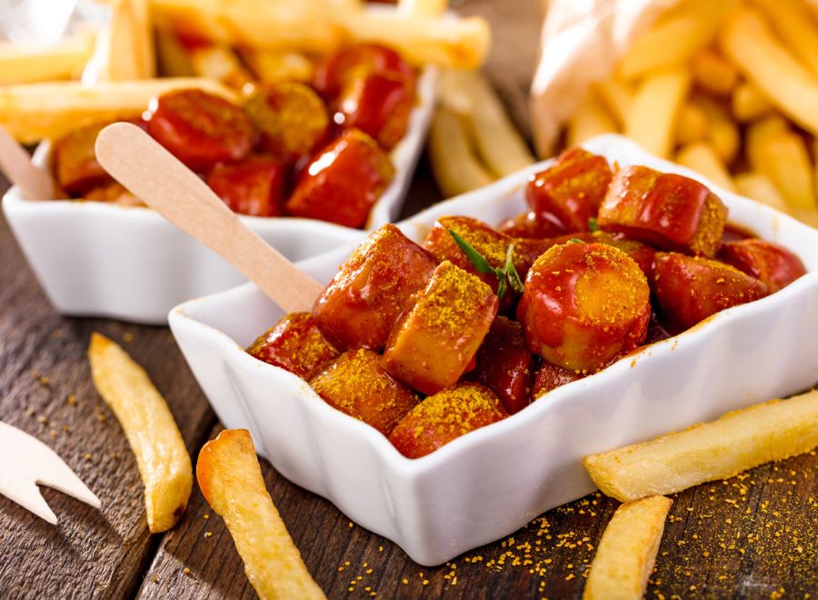 Currywurst sau khi nướng chín được rưới thêm sốt cà ri thơm lừng và một ít bột ớt cực kỳ hấp dẫn